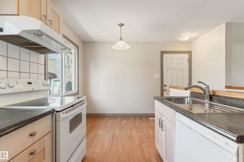 Kitchen featuring wood-finish flooring and light-toned walls - 10620 68 Avenue, Edmonton, AB - Indoor Photo Showing Kitchen With Double Sink