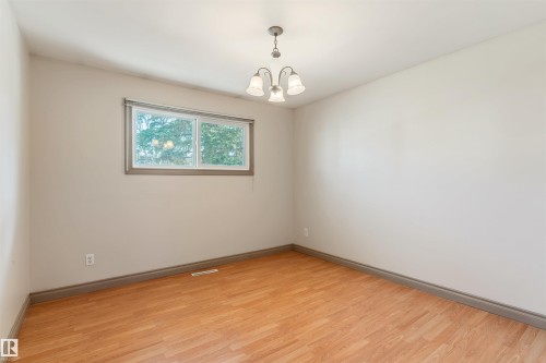 Bright interior space featuring wood-finish flooring, a window with a dark trim, and a ceiling-mounted light fixture - 10620 68 Avenue, Edmonton, AB - Indoor Photo Showing Other Room