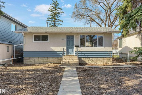 Bungalow-style residence featuring a light-colored stucco exterior with blue siding accents - 10620 68 Avenue, Edmonton, AB - Outdoor