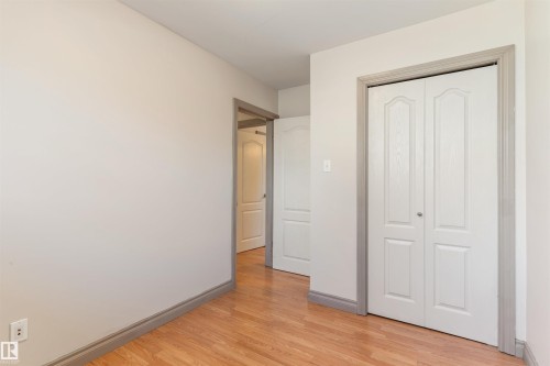 Room featuring light wood-finish flooring, light neutral wall paint, and white bi-fold closet doors with panel detailing - 10620 68 Avenue, Edmonton, AB - Indoor Photo Showing Other Room