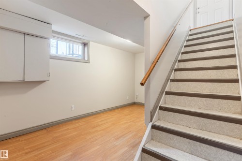 Finished lower level room featuring wood-finish flooring, a single window, and built-in white cabinetry - 10620 68 Avenue, Edmonton, AB - Indoor Photo Showing Other Room