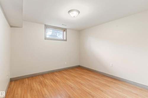 Room featuring wood-finish flooring, neutral wall tones, baseboard trim, and a high-set window - 10620 68 Avenue, Edmonton, AB - Indoor Photo Showing Other Room