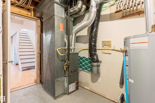 Utility area featuring a furnace, water heater, and exposed overhead piping - 10620 68 Avenue, Edmonton, AB - Indoor Photo Showing Basement