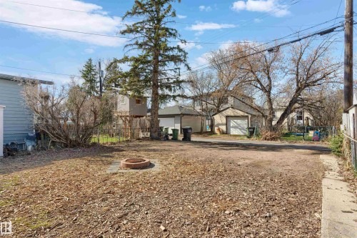 Spacious yard area featuring a built-in fire pit, mature trees, and a gravel driveway - 10620 68 Avenue, Edmonton, AB - Outdoor