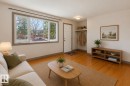 Living area featuring wood-finish flooring, a large multi-pane window, and a built-in entry shelf with a hanging rod - 10620 68 Avenue, Edmonton, AB  - Indoor Photo Showing Living Room 