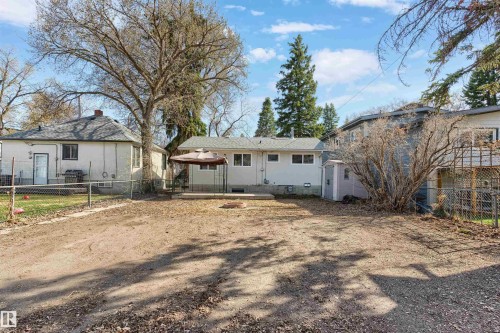 Expansive backyard with a concrete patio, mature trees, and a storage shed - 10620 68 Avenue, Edmonton, AB - Outdoor