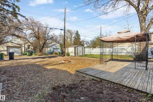Spacious backyard featuring a wood deck, mature trees, and a fire pit area - 10620 68 Avenue, Edmonton, AB - Outdoor