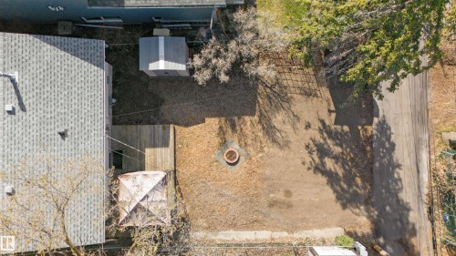 Expansive backyard with a central fire pit feature, wood-plank deck, and a utility shed - 10620 68 Avenue, Edmonton, AB - Outdoor