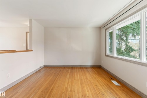 Bright living space featuring natural hardwood flooring and large windows with grey trim - 10620 68 Avenue, Edmonton, AB - Indoor Photo Showing Other Room