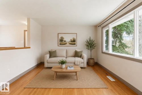 Living room featuring hardwood flooring, white walls, and a large multi-pane window with grey trim - 10620 68 Avenue, Edmonton, AB - Indoor Photo Showing Living Room