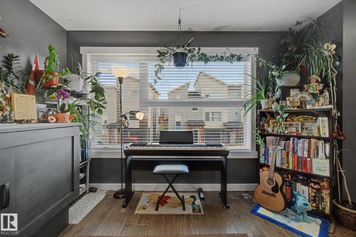 Spacious room with wood-finish flooring, dark wall paint, and a large window - 210 401 Southfork Drive, Leduc, AB - Indoor