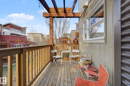 Wood-plank balcony featuring a wooden railing, overhead pergola, and string lighting - 210 401 Southfork Drive, Leduc, AB - Outdoor With Deck Patio Veranda With Exterior