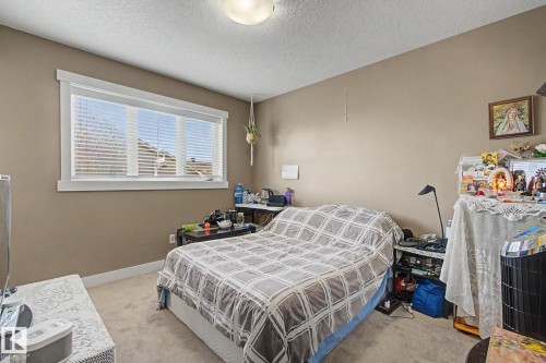 Carpeted room with neutral-toned walls, featuring a large window with white trim and blinds - 210 401 Southfork Drive, Leduc, AB - Indoor Photo Showing Bedroom