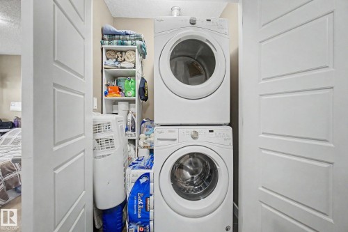 Dedicated laundry closet featuring a stacked washer and dryer unit - 210 401 Southfork Drive, Leduc, AB - Indoor Photo Showing Laundry Room