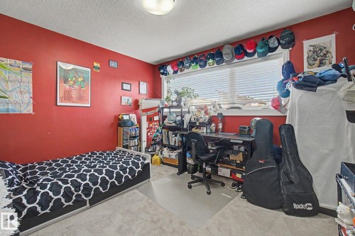 Carpeted interior room featuring a large window with horizontal blinds, a ceiling-mounted light fixture, and a built-in shelving unit - 210 401 Southfork Drive, Leduc, AB - Indoor Photo Showing Bedroom