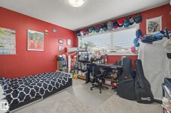 Carpeted interior room featuring a large window with horizontal blinds, a ceiling-mounted light fixture, and a built-in shelving unit - 