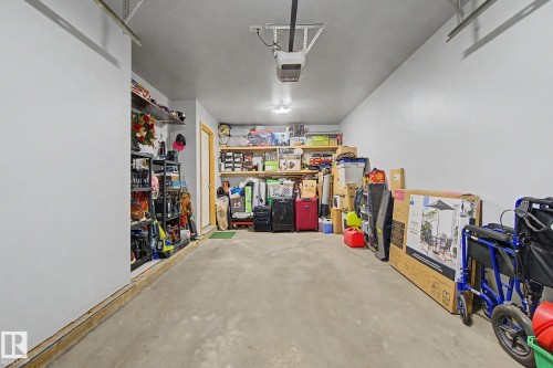Garage interior featuring concrete flooring, painted walls, overhead lighting, and built-in shelving - 210 401 Southfork Drive, Leduc, AB - Indoor