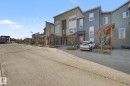 Modern townhome featuring a multi-story facade with varied siding textures, a covered entry porch, dark trim accents, and a distinctive sloped roofline - 210 401 Southfork Drive, Leduc, AB  - Outdoor 