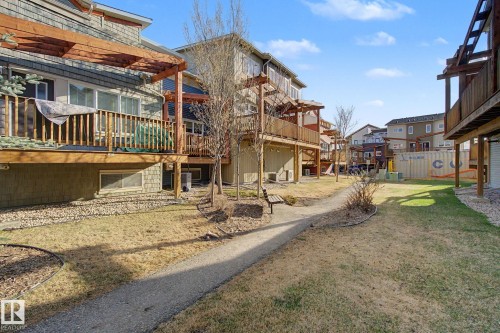 Community green space with a gravel pathway, complemented by mature trees and a dedicated bench area - 210 401 Southfork Drive, Leduc, AB - Outdoor
