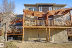Multi-level townhome featuring a rear wooden deck with a pergola, exterior siding in varying shades, and ground-level gravel landscaping - 