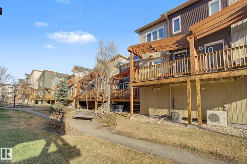 Rear exterior featuring a multi-level wood deck with pergola, gravel landscaping, and a paved walkway - 210 401 Southfork Drive, Leduc, AB - Outdoor With Balcony
