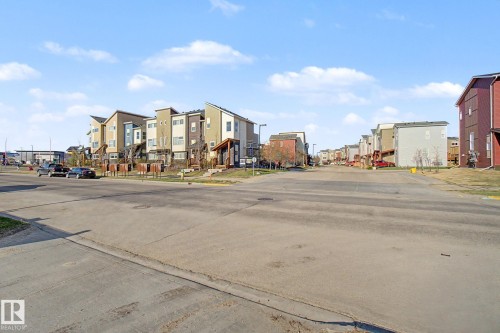 Streetscape featuring a collection of multi-story townhomes with varied exterior finishes, including siding and stucco elements - 210 401 Southfork Drive, Leduc, AB - Outdoor