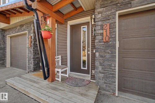 Wood-finish entry deck leading to a dark brown entry door with vertical window panel - 210 401 Southfork Drive, Leduc, AB - Outdoor With Exterior