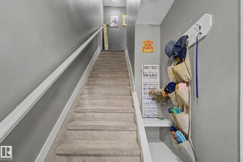 Carpeted staircase featuring white handrails and neutral gray wall paint - 210 401 Southfork Drive, Leduc, AB - Indoor Photo Showing Other Room