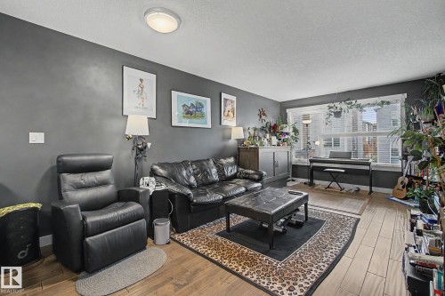 Spacious living area featuring wood-finish flooring, a broad window with blinds, and recessed lighting - 210 401 Southfork Drive, Leduc, AB - Indoor Photo Showing Living Room