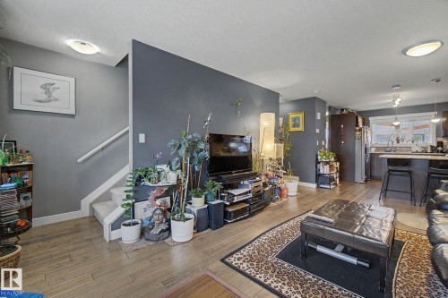 Spacious open-concept living area featuring wood-finish flooring, a contemporary dark accent wall, and recessed lighting - 210 401 Southfork Drive, Leduc, AB - Indoor Photo Showing Living Room