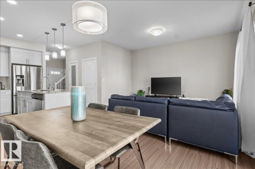 Open-concept living area featuring wood-finish flooring, white walls, and a modern drum pendant light - 2847 Koshal Crescent, Edmonton, AB - Indoor