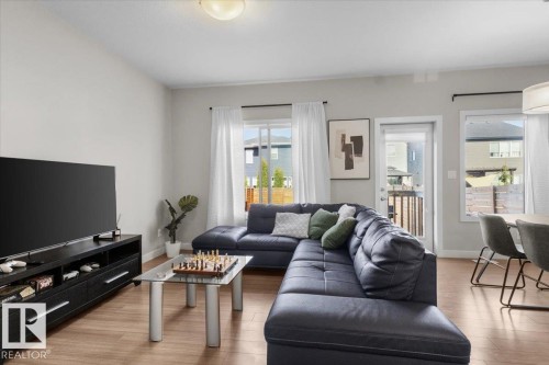 Open-concept living space featuring wood-finish flooring, light gray walls, and multiple windows - 2847 Koshal Crescent, Edmonton, AB - Indoor Photo Showing Living Room