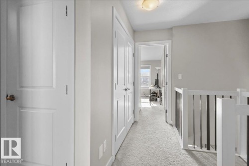 Hallway featuring light gray carpeting, white trim, and a white balustrade with black metal spindles - 2847 Koshal Crescent, Edmonton, AB - Indoor Photo Showing Other Room