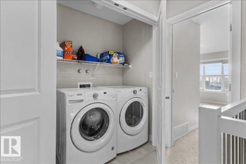Dedicated laundry closet featuring a stacked washer and dryer, convenient wire shelving, and neutral wall tones - 2847 Koshal Crescent, Edmonton, AB - Indoor Photo Showing Laundry Room