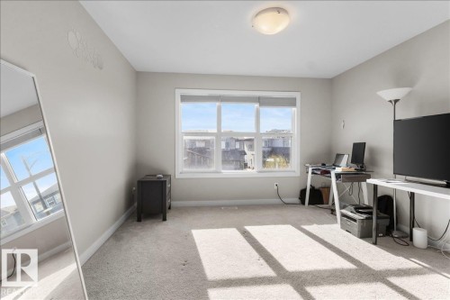 Carpeted room featuring a large window with white framing and a flush-mount ceiling light fixture - 2847 Koshal Crescent, Edmonton, AB - Indoor