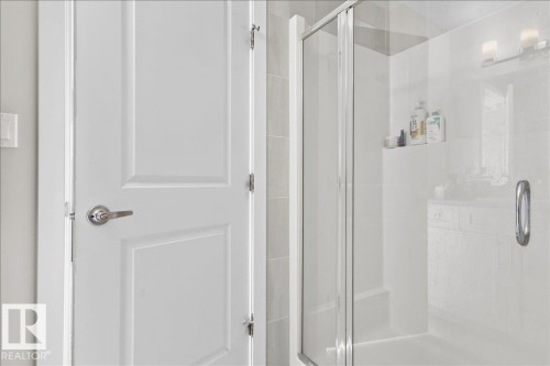 Walk-in shower with clear glass enclosure, white shower surround, and integrated shelving - 2847 Koshal Crescent, Edmonton, AB - Indoor Photo Showing Bathroom