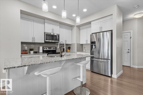 Contemporary kitchen featuring white cabinetry, stainless steel appliances, speckled countertops, and a gray subway tile backsplash - 2847 Koshal Crescent, Edmonton, AB - Indoor Photo Showing Kitchen With Stainless Steel Kitchen With Upgraded Kitchen