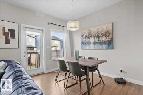 Dining area featuring a wood-finish flooring, a modern pendant light fixture, and a built-in deck access door - 2847 Koshal Crescent, Edmonton, AB - Indoor Photo Showing Dining Room