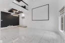 Spacious interior featuring a large projection screen, high ceilings, and a distinctive black accent wall with geometric paneling - 1827 17 Avenue, Edmonton, AB  -  Photo Showing Other Room 