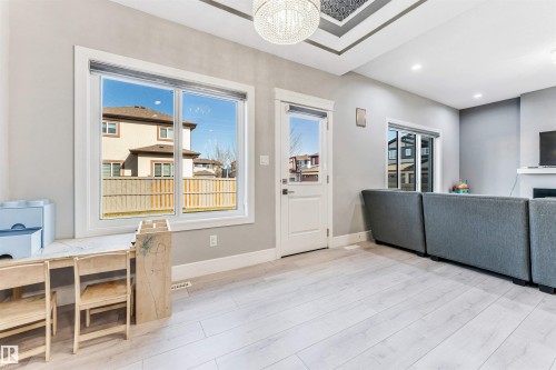 Spacious interior featuring light wood-finish flooring and a tray ceiling with a central chandelier - 1103 29 Street, Edmonton, AB - Indoor