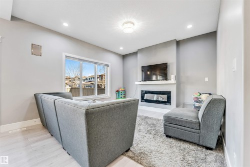 Living area featuring a contemporary electric fireplace with a white mantel, recessed lighting, and a large window - 1103 29 Street, Edmonton, AB - Indoor With Fireplace