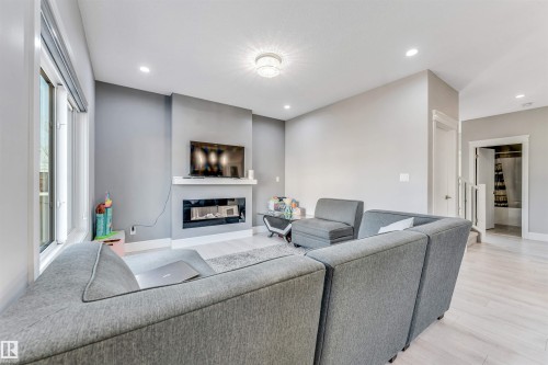 Living area featuring a contemporary fireplace with a white mantle, expansive windows, recessed lighting, and light wood-finish flooring - 1103 29 Street, Edmonton, AB - Indoor With Fireplace
