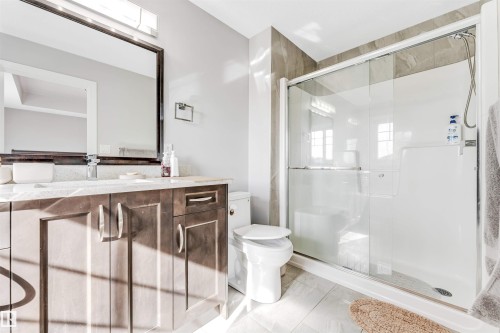 Bathroom featuring a dark wood-finish vanity with a light-colored countertop, an undermount sink, and a large framed mirror - 1103 29 Street, Edmonton, AB - Indoor Photo Showing Bathroom