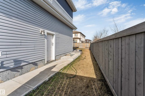 Side yard featuring a concrete walkway, light blue horizontal siding, and a white exterior door - 1103 29 Street, Edmonton, AB - Outdoor With Exterior