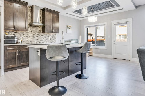 Modern kitchen featuring dark wood cabinetry, light countertops, and a mosaic tile backsplash - 1103 29 Street, Edmonton, AB - Indoor