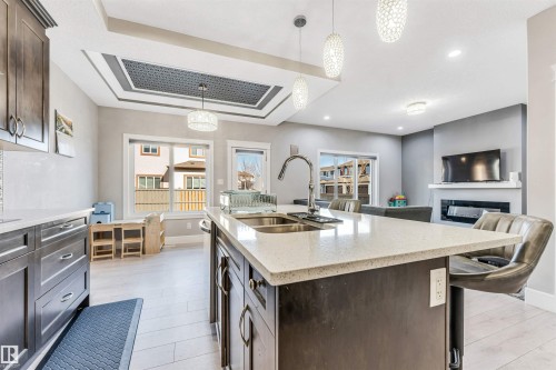 Open-concept kitchen with a large island featuring a double sink and ample counter space, dark wood-finish cabinetry, and recessed lighting - 1103 29 Street, Edmonton, AB - Indoor Photo Showing Kitchen With Double Sink With Upgraded Kitchen