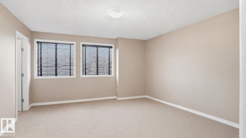 Carpeted room featuring two windows with horizontal blinds, neutral-toned walls, white baseboards, and a semi-flush mount ceiling light fixture - 1709 64 Street, Edmonton, AB - Indoor Photo Showing Other Room