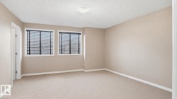 Carpeted room featuring two windows with horizontal blinds, neutral-toned walls, white baseboards, and a semi-flush mount ceiling light fixture - 