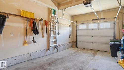 Garage featuring a sectional overhead door with upper window inserts and an automatic opener - 1709 64 Street, Edmonton, AB - Indoor Photo Showing Garage