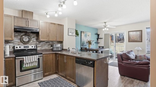 Kitchen featuring stainless steel appliances, wood-finish cabinetry, a tiled backsplash, and a breakfast bar - 1709 64 Street, Edmonton, AB - Indoor Photo Showing Kitchen With Double Sink